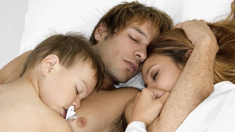 Casal com filho a dormir numa cama
